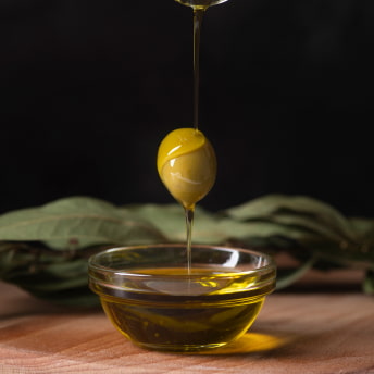 Oliva con un chorro de aceite cayendo encima