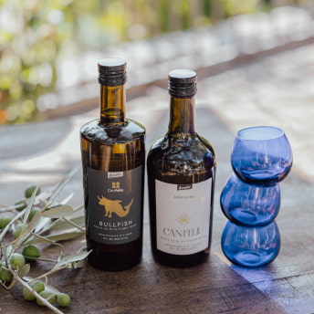 Botella aceite, vasos y rama de olivo en bodegón